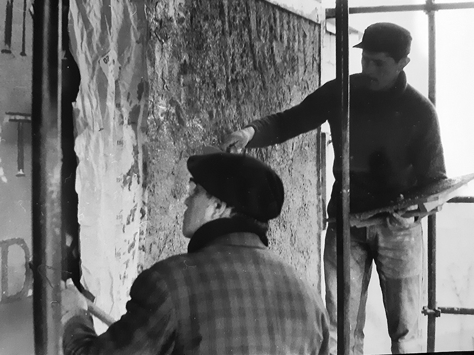 Jean Amblard gravant le ciment frais au côté du maçon.